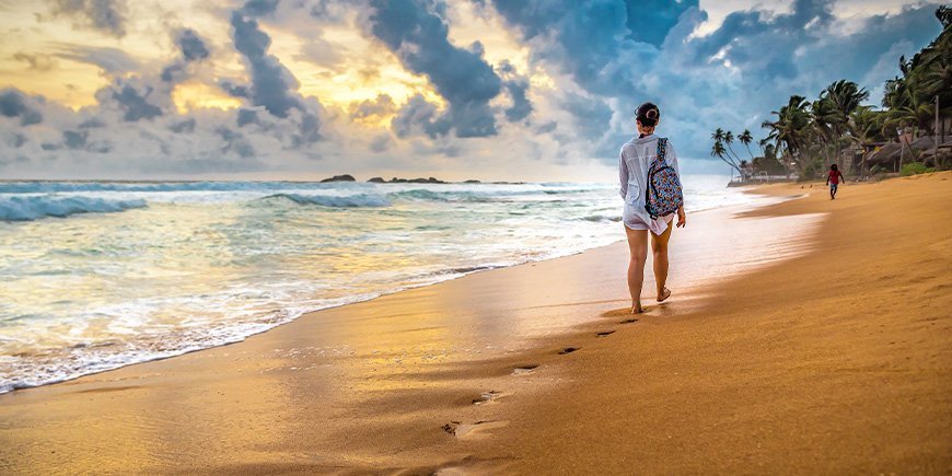 Kvinne går tur på stranden i Sri Lanka