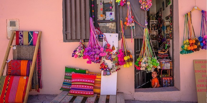 Liten lokal butikk i Purmamarca, Argentina, og en jente som sitter i døråpningen.