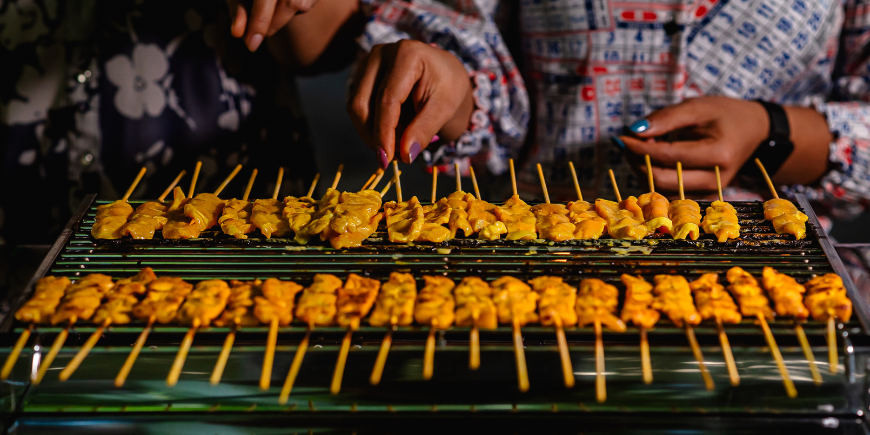 Kvinner som tilbereder moo satay på grillen