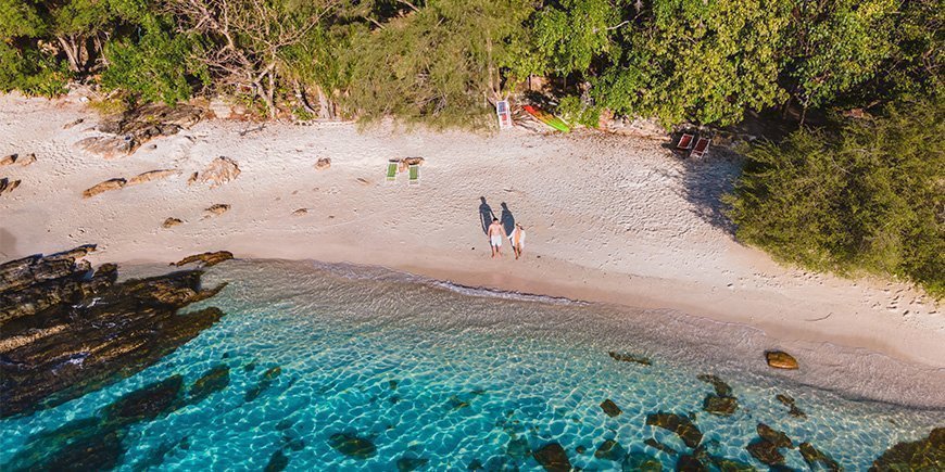 Par som holder hverandre i hånden på stranden på Koh Samet