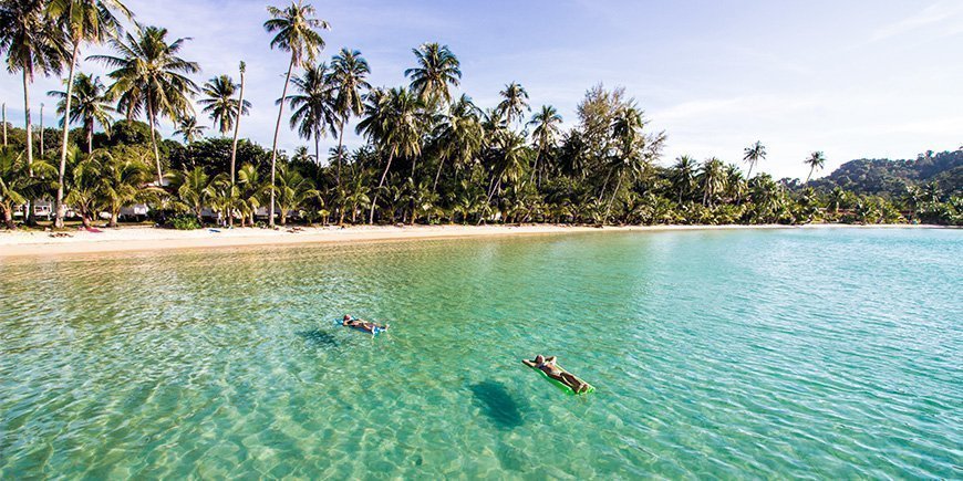 Folk slapper av i vannet på stranden på Koh Kood