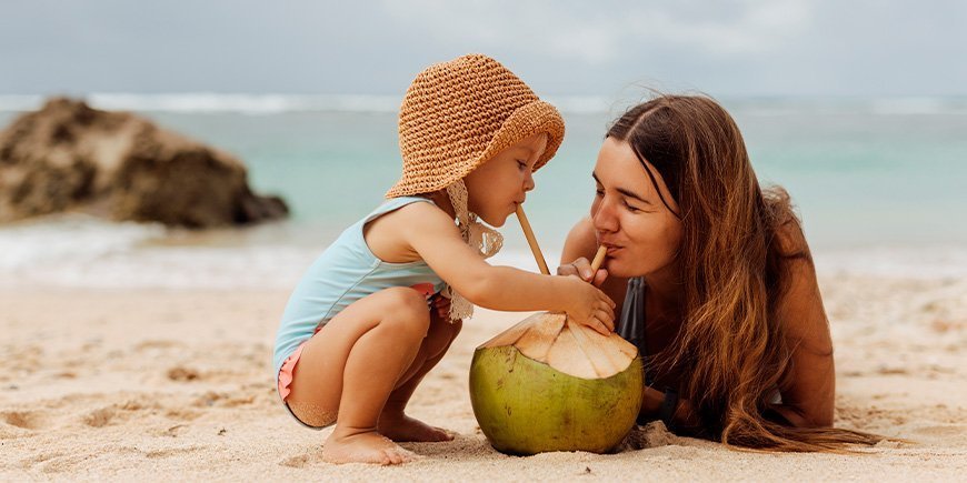 Ung kvinne og barn på en strand i Thailand