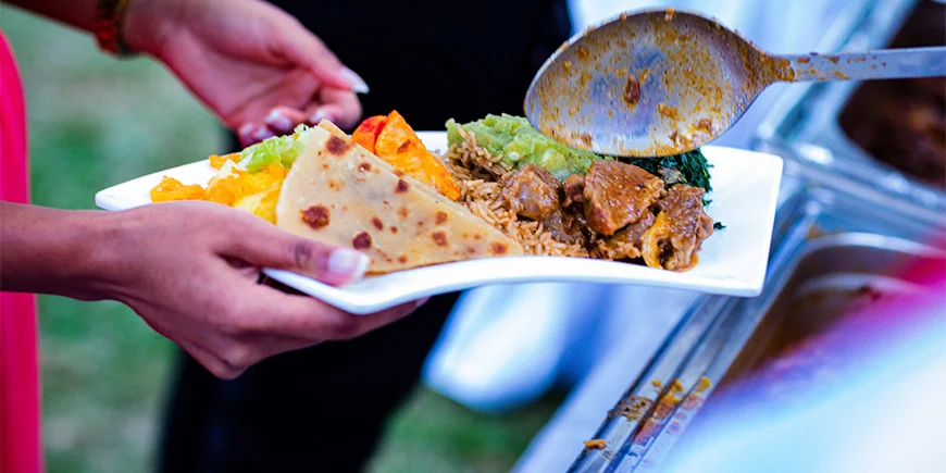 Kvinne som holder en tallerken med mat i Kenya.