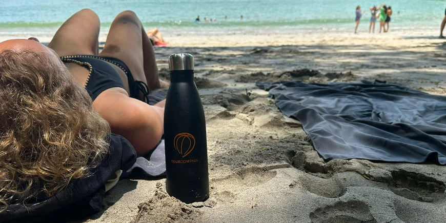 Kvinne ligger i sanden på en solrik dag på en strand i Costa Rica.