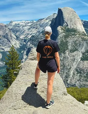 Kvinne i TourCompass-t-skjorte på klippe i Yosemite
